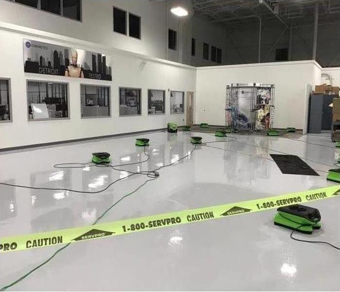 Water loss in a large warehouse with fans and caution tape 