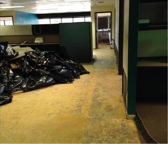 Black garbage bags piled up with demolition materials in an empty office building